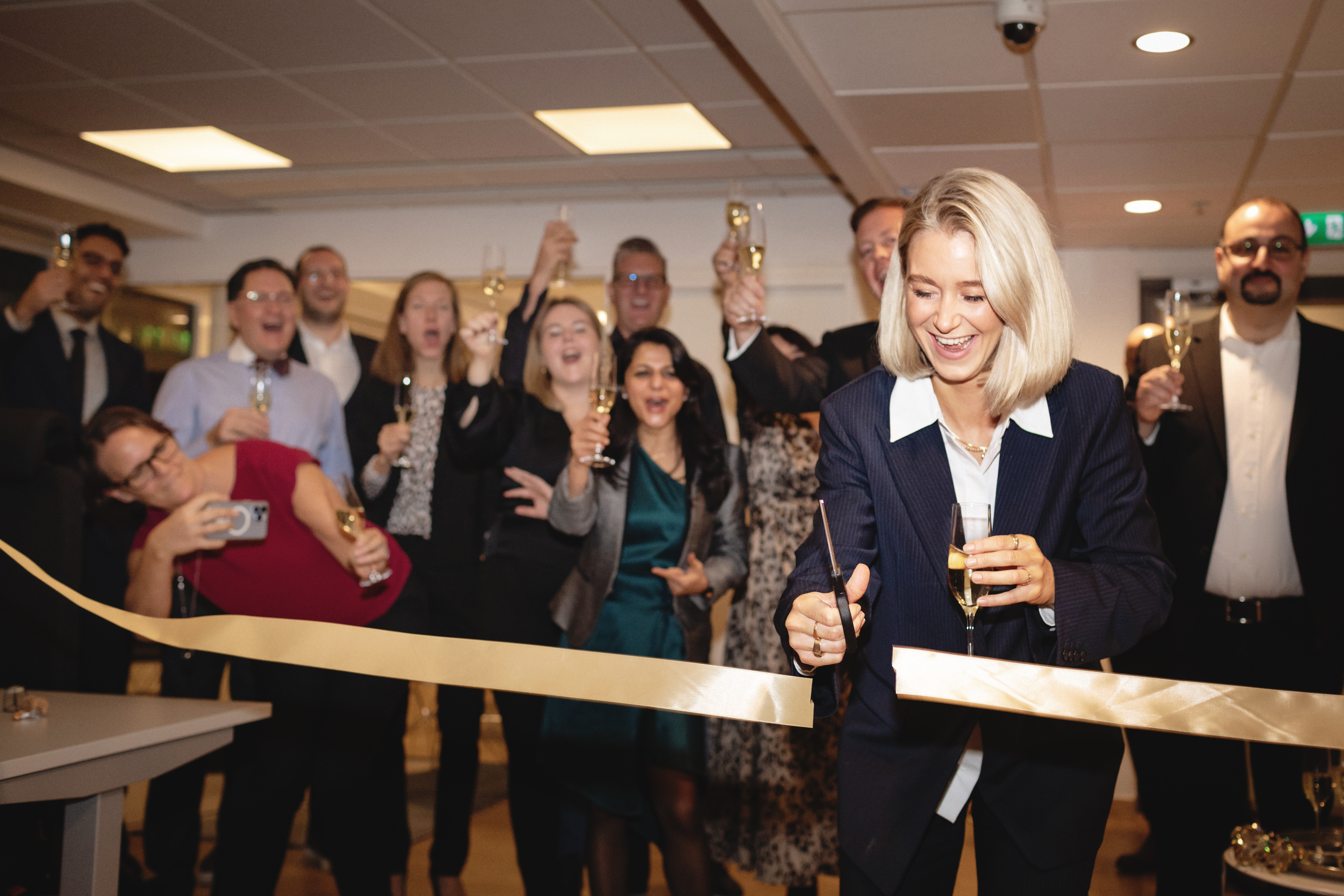 Andersson cuts a ribbon at an event as colleagues celebrate behind her. 
