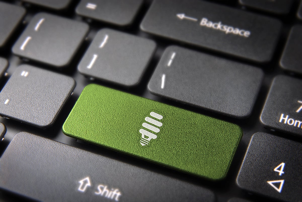 Green energy key with eco bulb light icon on laptop keyboard