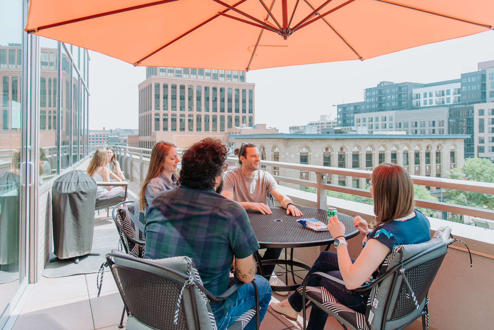 Employees of Pie Insurance sitting at a table on their office balcony, overlooking the city.