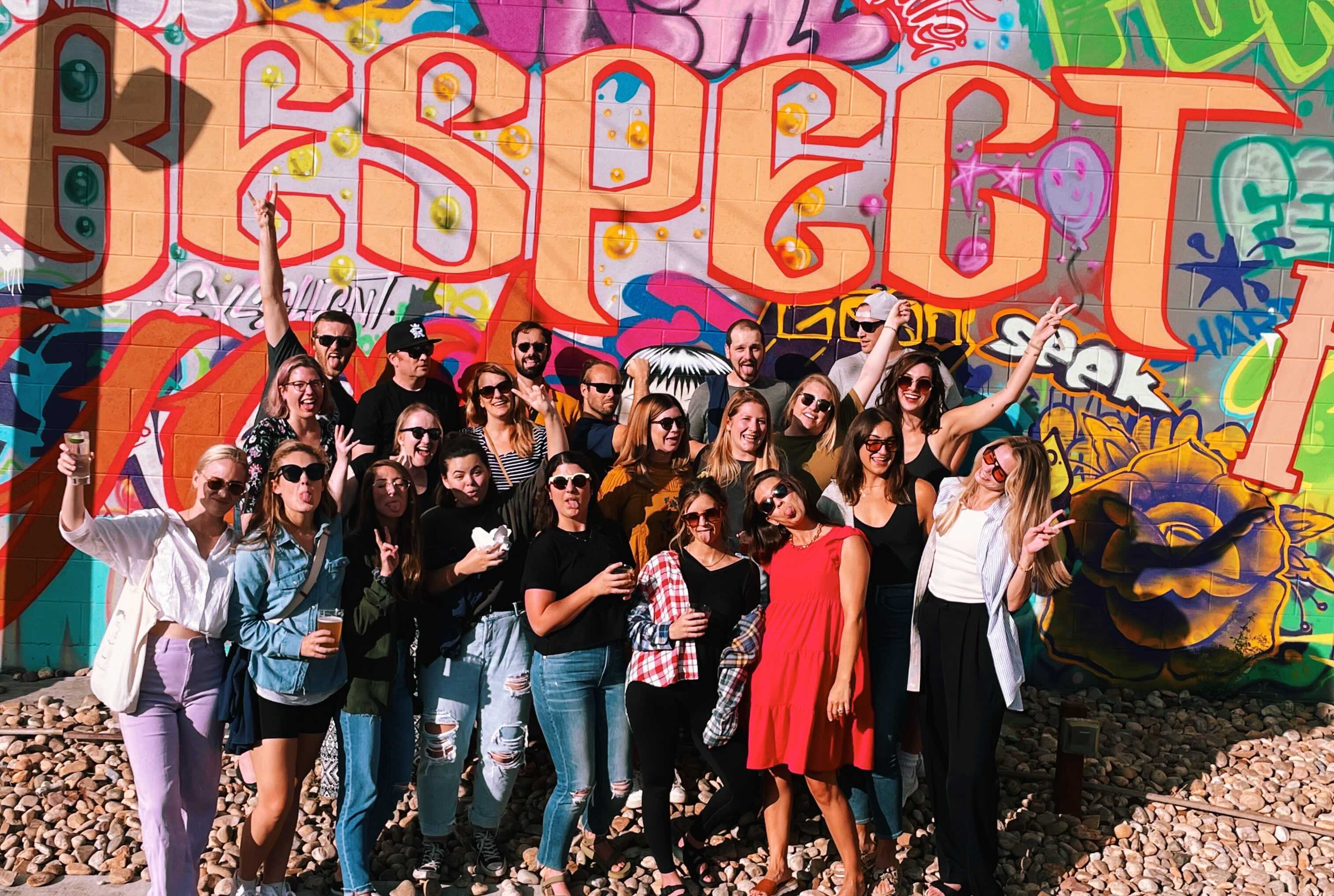 Team outing in front of colorful graffiti spelling "respect."