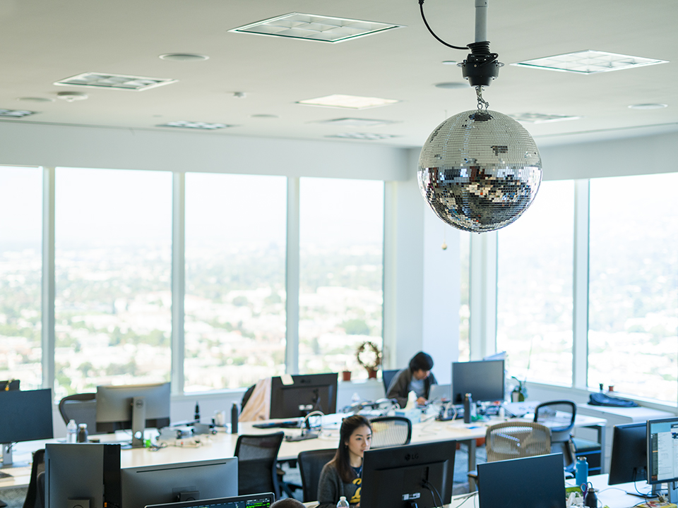 Team members working in the DISQO office with a disco ball hanging from the ceiling