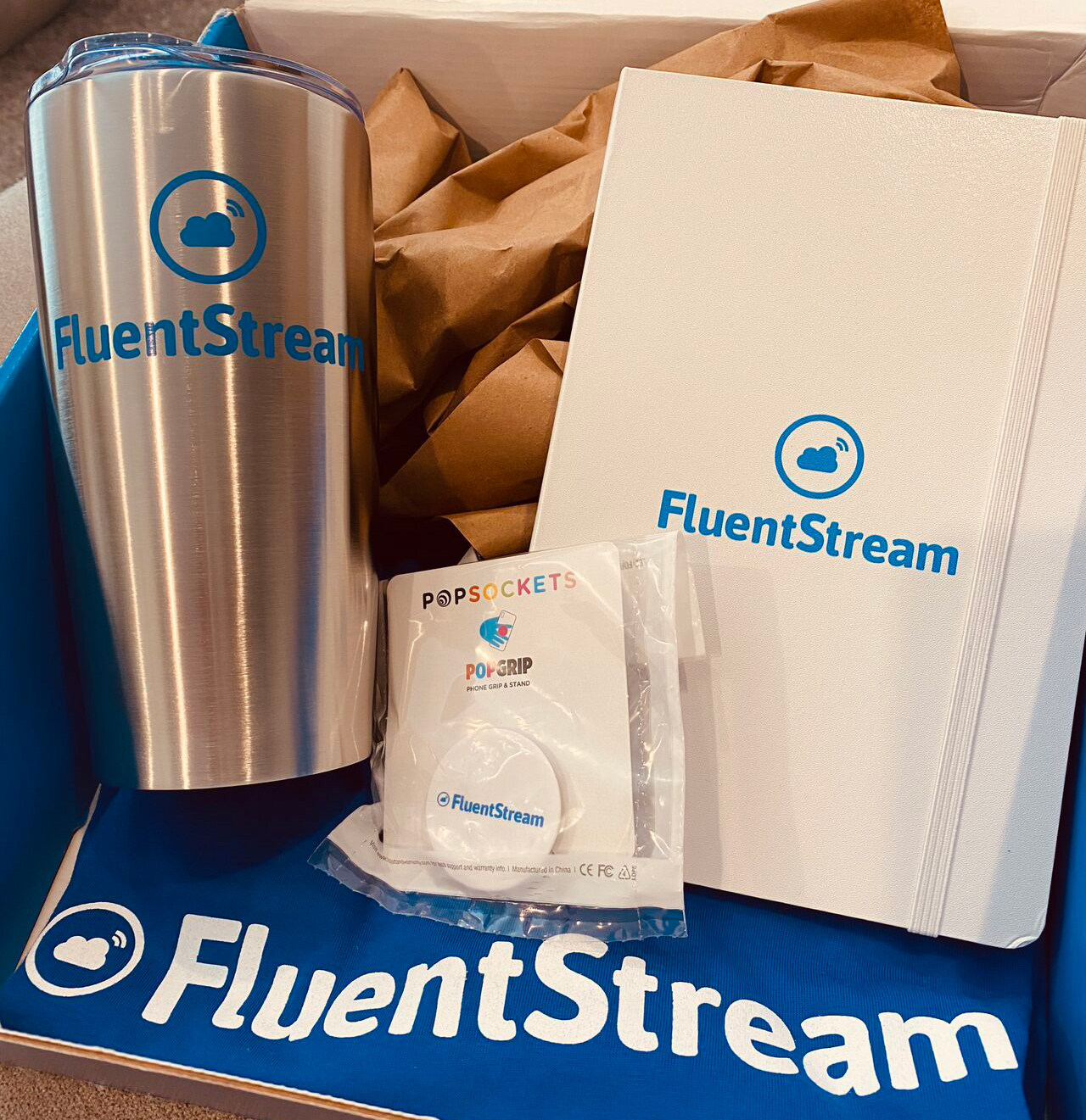 Tumbler, journal, pop socket and t-shirt with the FluentStream logo on them