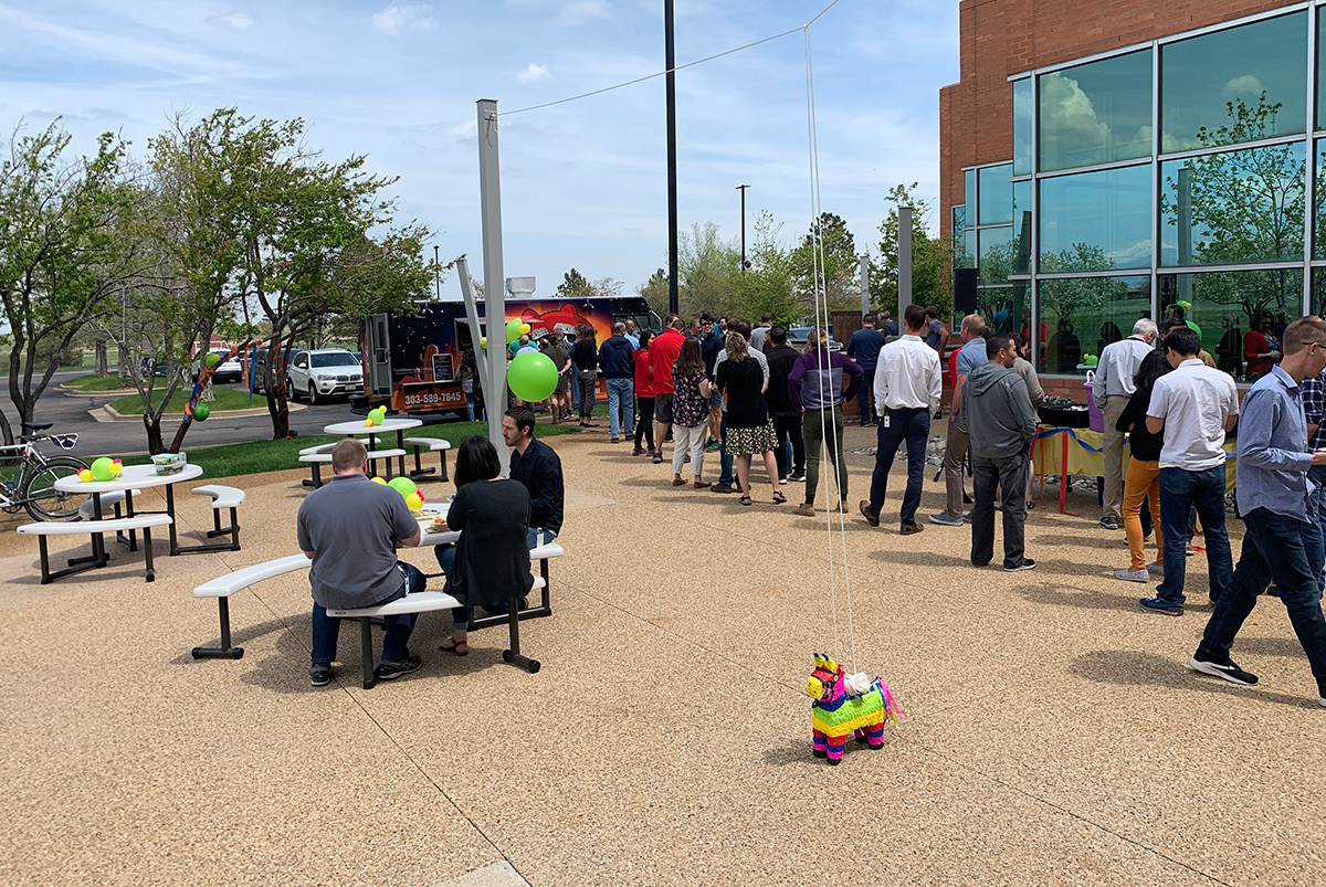 GHX team members at an outdoor gathering with a food truck and a pinata