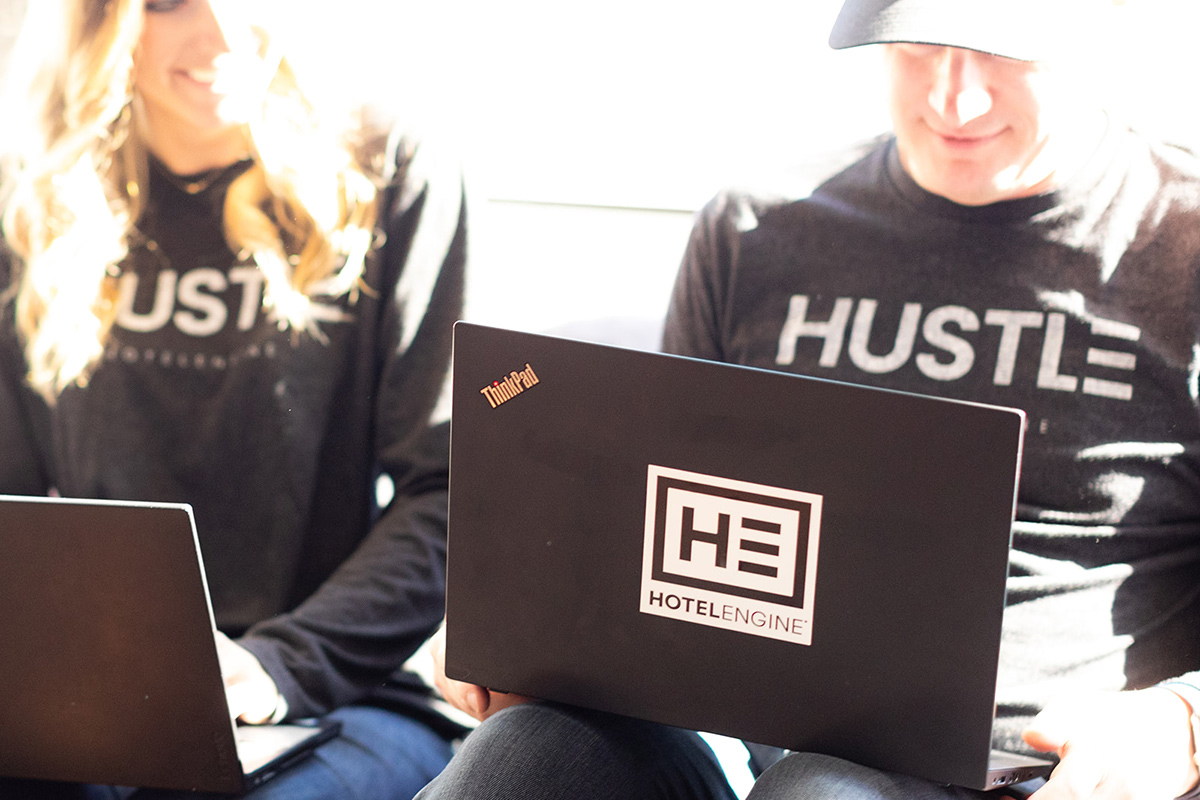 Close up of Hotel Engine team members working on laptops with the company logo on them