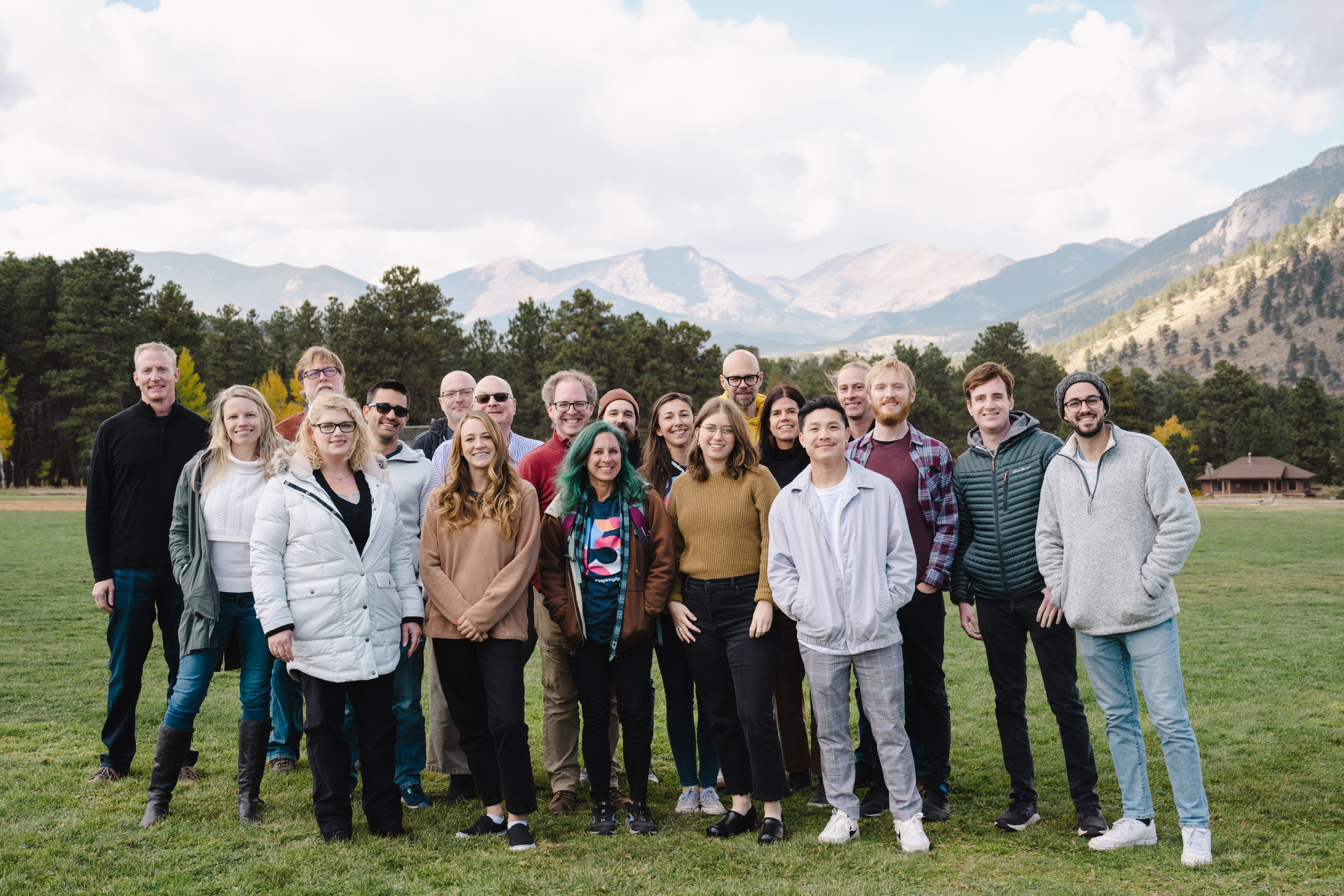  The InspiringApp team gathered in front of a mountain range on green grass.