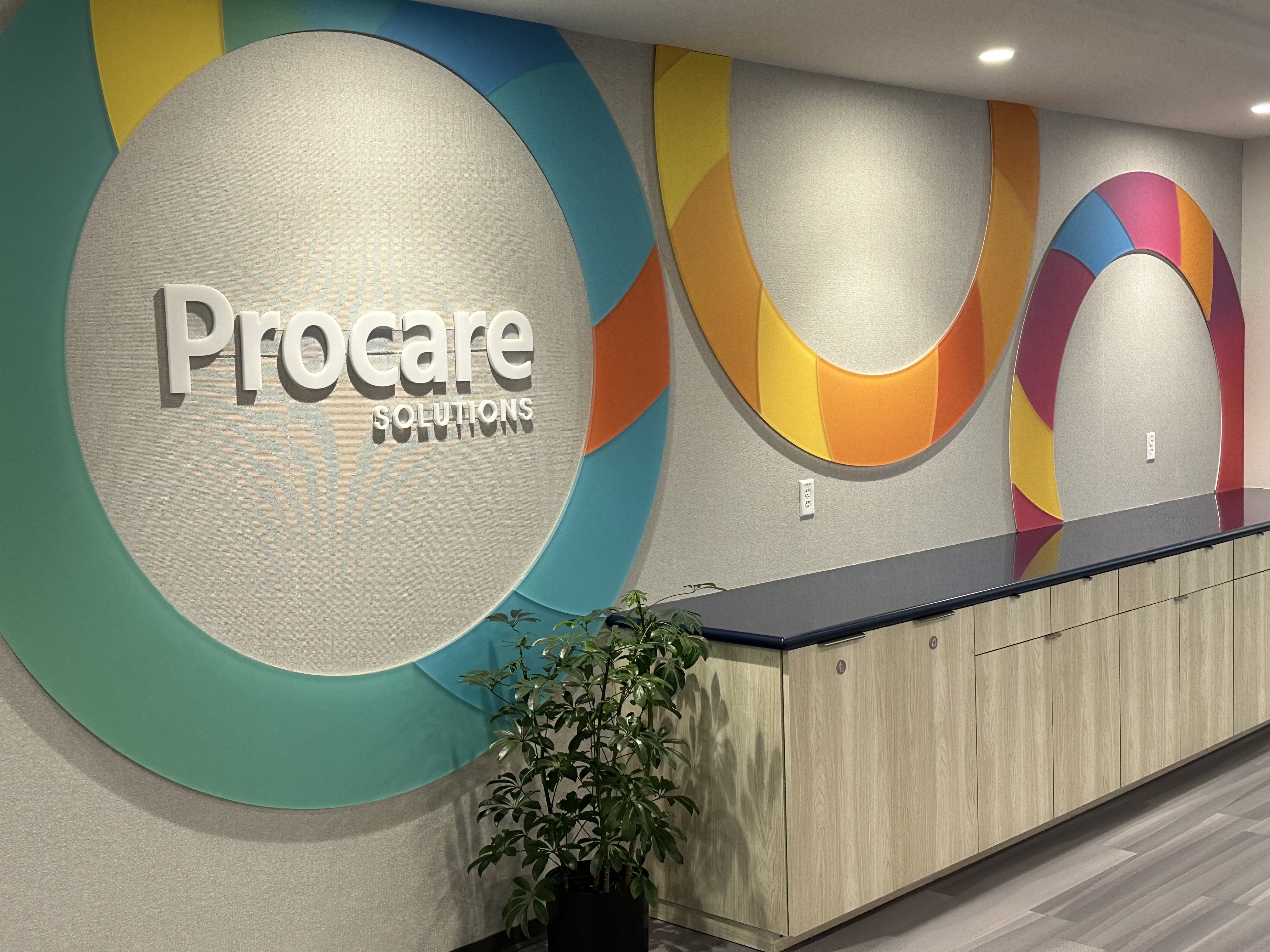 Photo of Procare Solutions’ office wall with logo and colorful circles