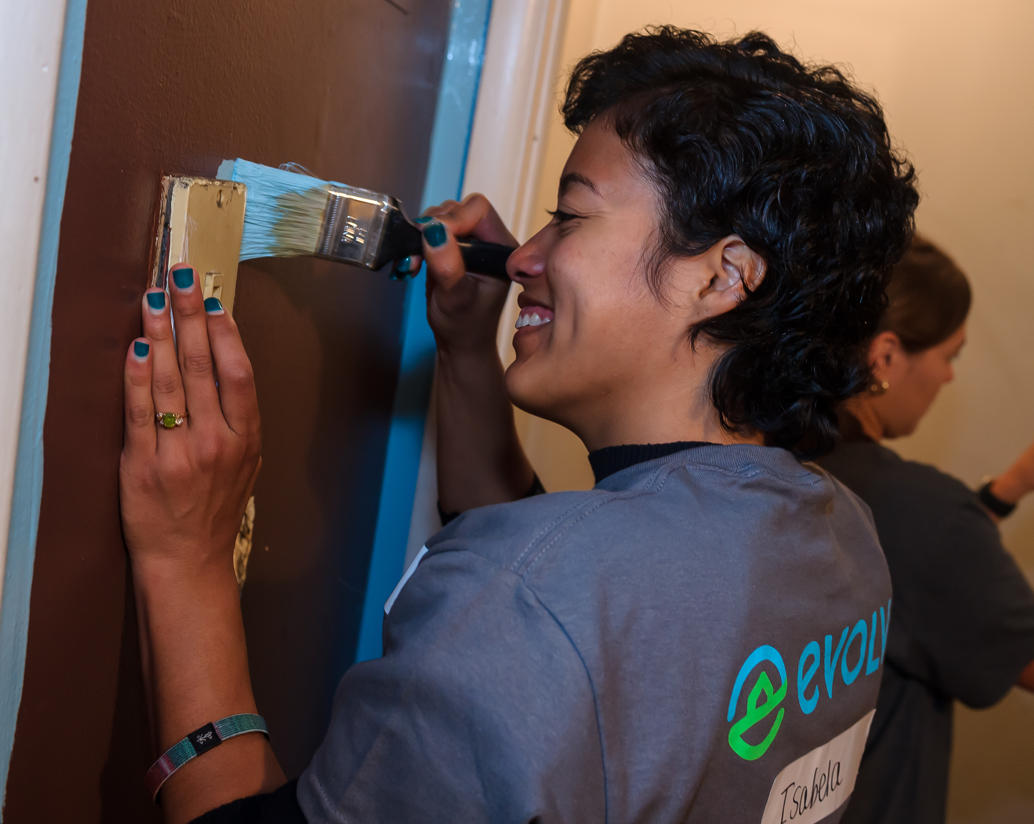 An Evolve team member brushes sky blue paint on a door during a community service event. 