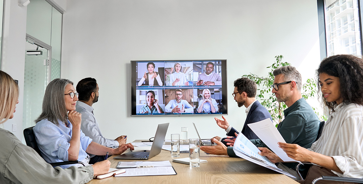company employees having online business conference video call on tv screen monitor in board meeting room