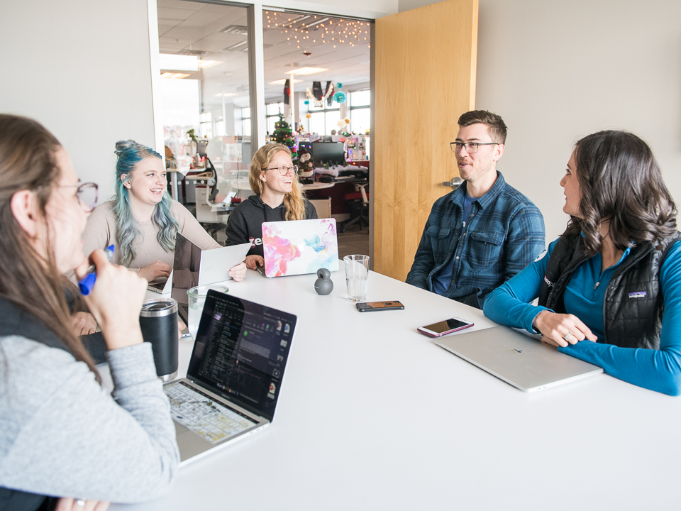 A group of happy-looking Zen Planner employees sitting around a meeting table.