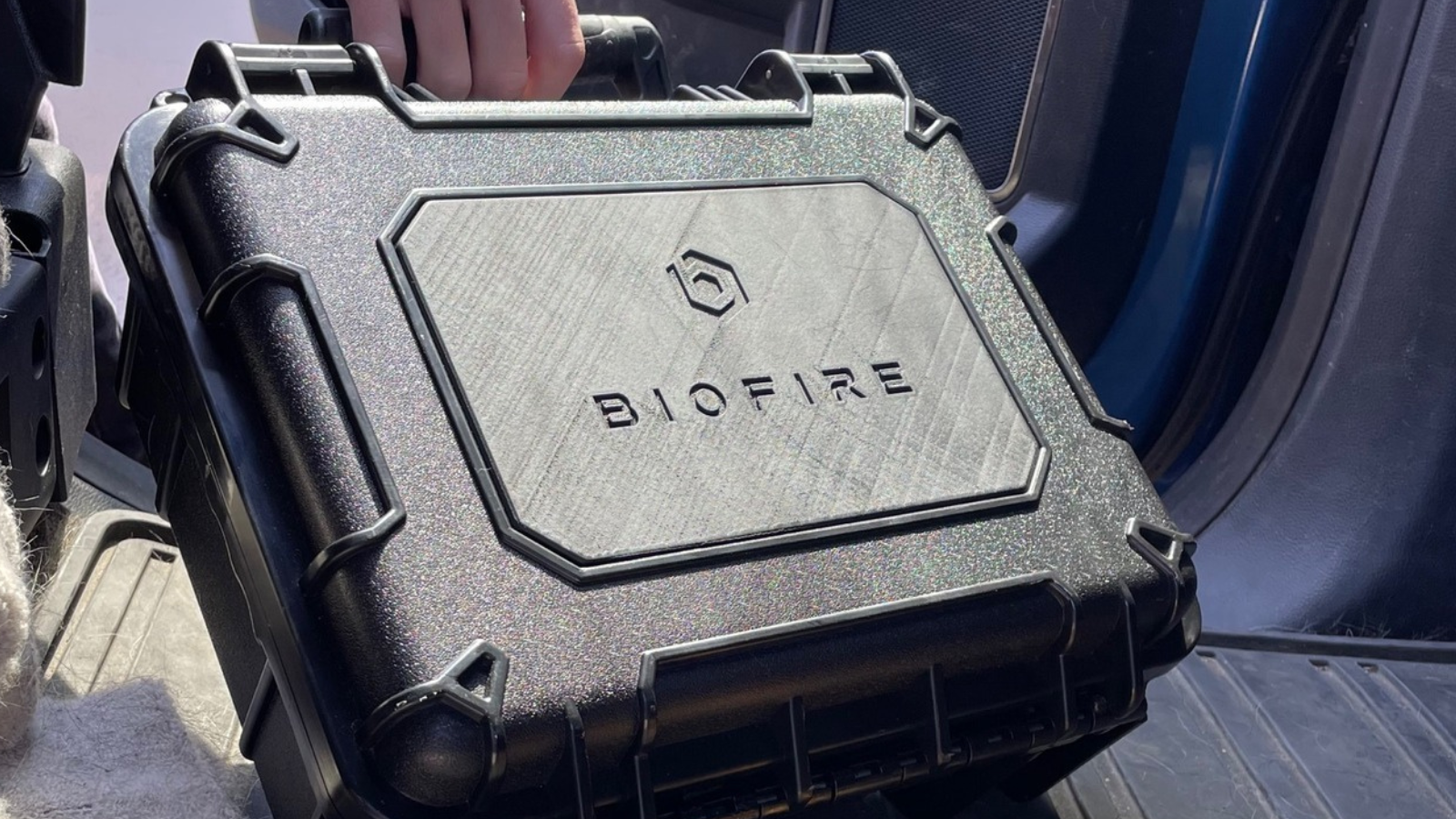 A person taking a Biofire gun case out of a car. 