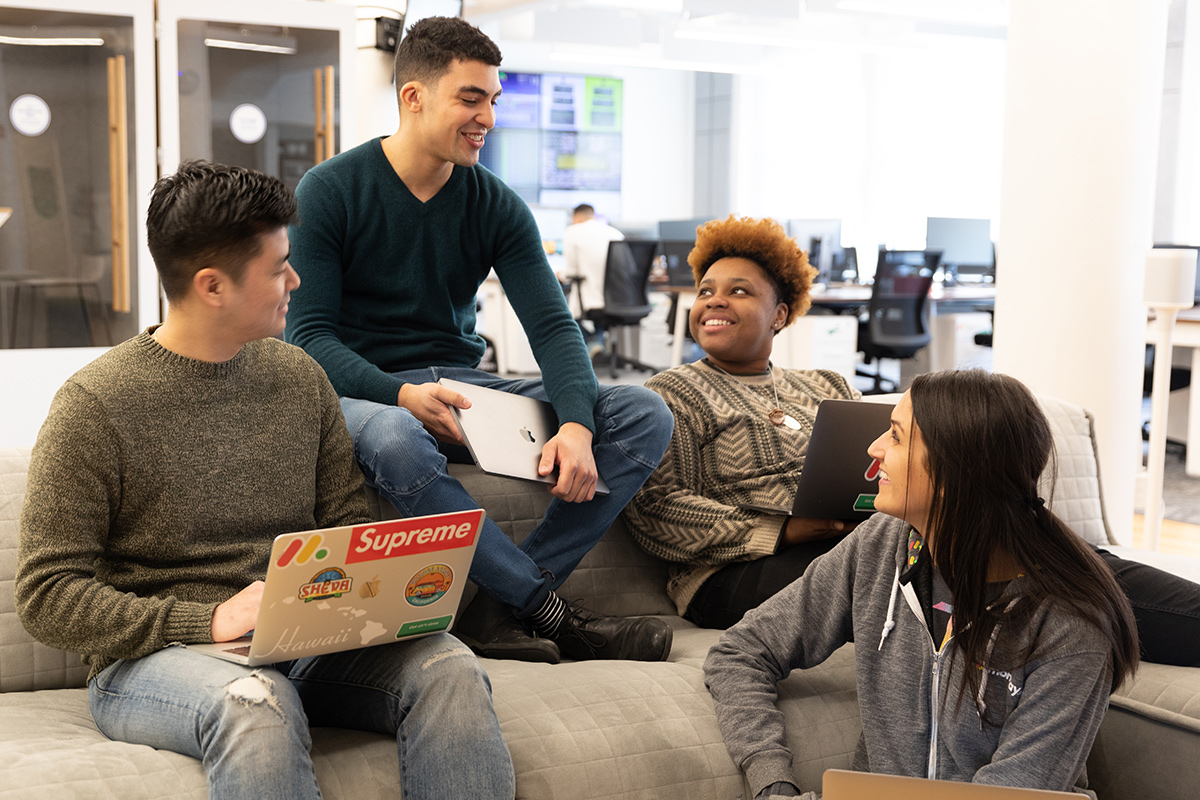 monday.com coworkers sitting on a couch bonding and having a team huddle