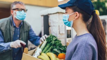 A woman holds a box of donated produce.