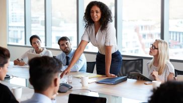 A woman leads a sales meeting for her team.