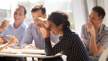 A group of employees laugh during a team lunch.