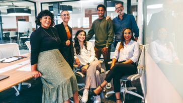 Group of happy businesspeople smiling at the camera in a boardroom.