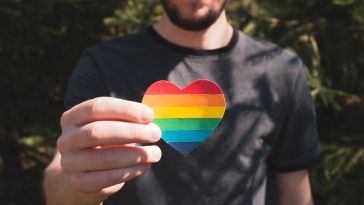 Man holding a paper heart in the colors of rainbow