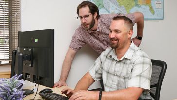 Two KPA colleagues looking at a computer monitor working on a project together