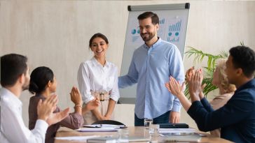 male leader praising a female colleague in a meeting