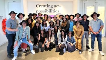 A group photo of the Udemy team wearing matching wide brimmed hats. 