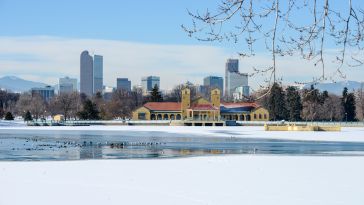 skyline photo of Denver in the snow with a forzen lake in the foreground
