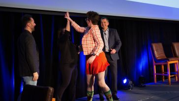 Photo of Lottie high-fiving a colleague as she takes the stage, winning Samban of the Year