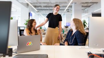 Employees talking at a desk, smiling