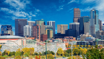 The Denver skyline with Elitch Gardens in the foreground. A rollercoaster is visible.