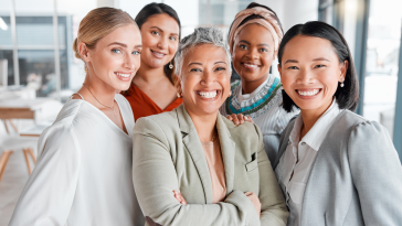 Diverse group of five women in business attire in an office setting