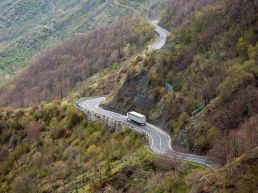 A truck driving on a long winding road through the mountains