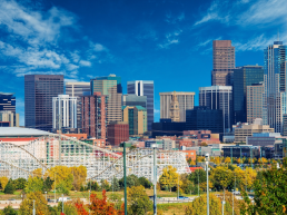 The Denver skyline with Elitch Gardens in the foreground. A rollercoaster is visible.